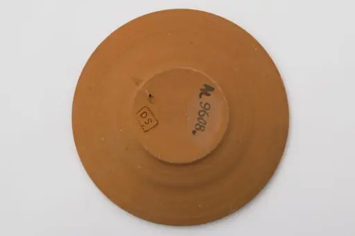 Vas ceramic cu fundul plat puțin adâncit și marginile evazate, puțin ridicate. Ornamentată cu pensula cu angoba albă. Fundul este marcat printr-o spirală din care ies alte șase spirale mici dispuse pe circumferința exterioară. Pe marginea vasului două benzi, una cu o linie întreruptă, a doua cu șase valuri întrerupte. La posterior ștanțat ”DS” încadrat într-un dreptunghi. Cromatică: fond: cărămiziu; motive: alb.
