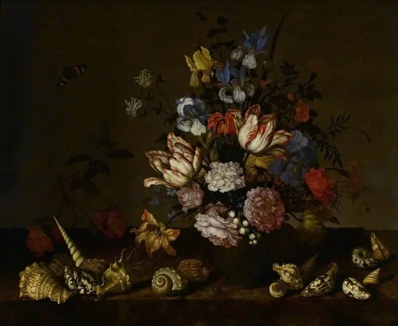 A vase of flowers with shells on a ledge