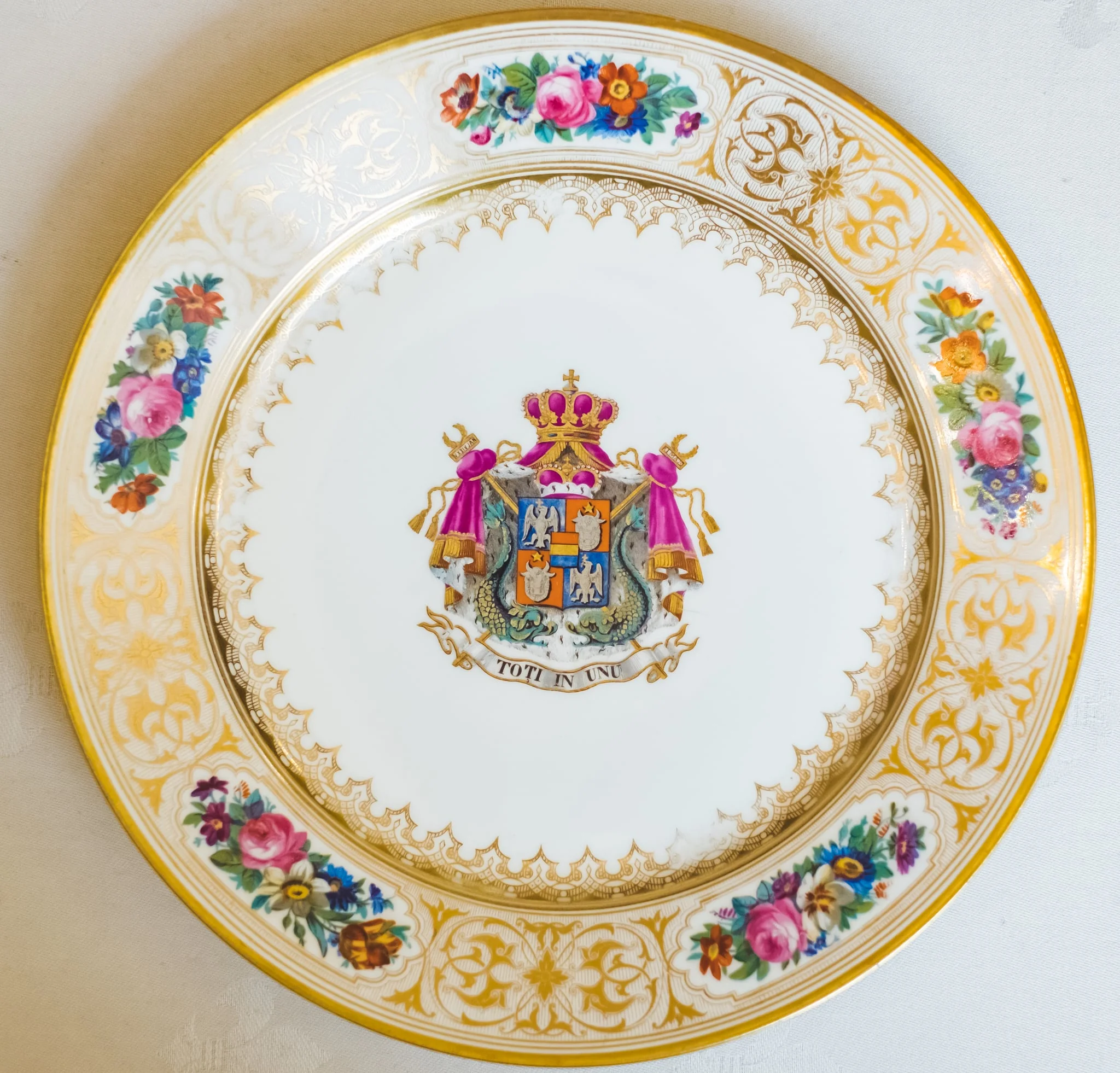 Farfurie, model decorativ stil Louis-Philippe, ales pentru serviciul de masa de peste 100 de piese Cuza, comandat la manufacturile regale din Sevres. Acesta urma să fie folosit de familia domnitoare Cuza în palatul de la Cotroceni. Farfuria este întinsă, circulară, pictată pe margini cu cinci medalioane florale care alternează cu arabescuri aurii. Este decorată central cu stema Principatelor Române și deviza unionistă „Toți în Unu". Stema și motivele florale se caracterizează printr-o vie policromie: galben, auriu, nuanțe de roșu, roz, verde și albastru. Pe reversul ei apar două marci în câmp circular: „Chateaux de Trianon" (culoare roșu carmin) și „Sevres 1846" (cu albastru). De asemenea, se remarcă cartelul care conține, în cifre latine, datele dublei alegeri a lui Al. I. Cuza ca principe al Moldovei și Țării Românești., by Unknown, 1850