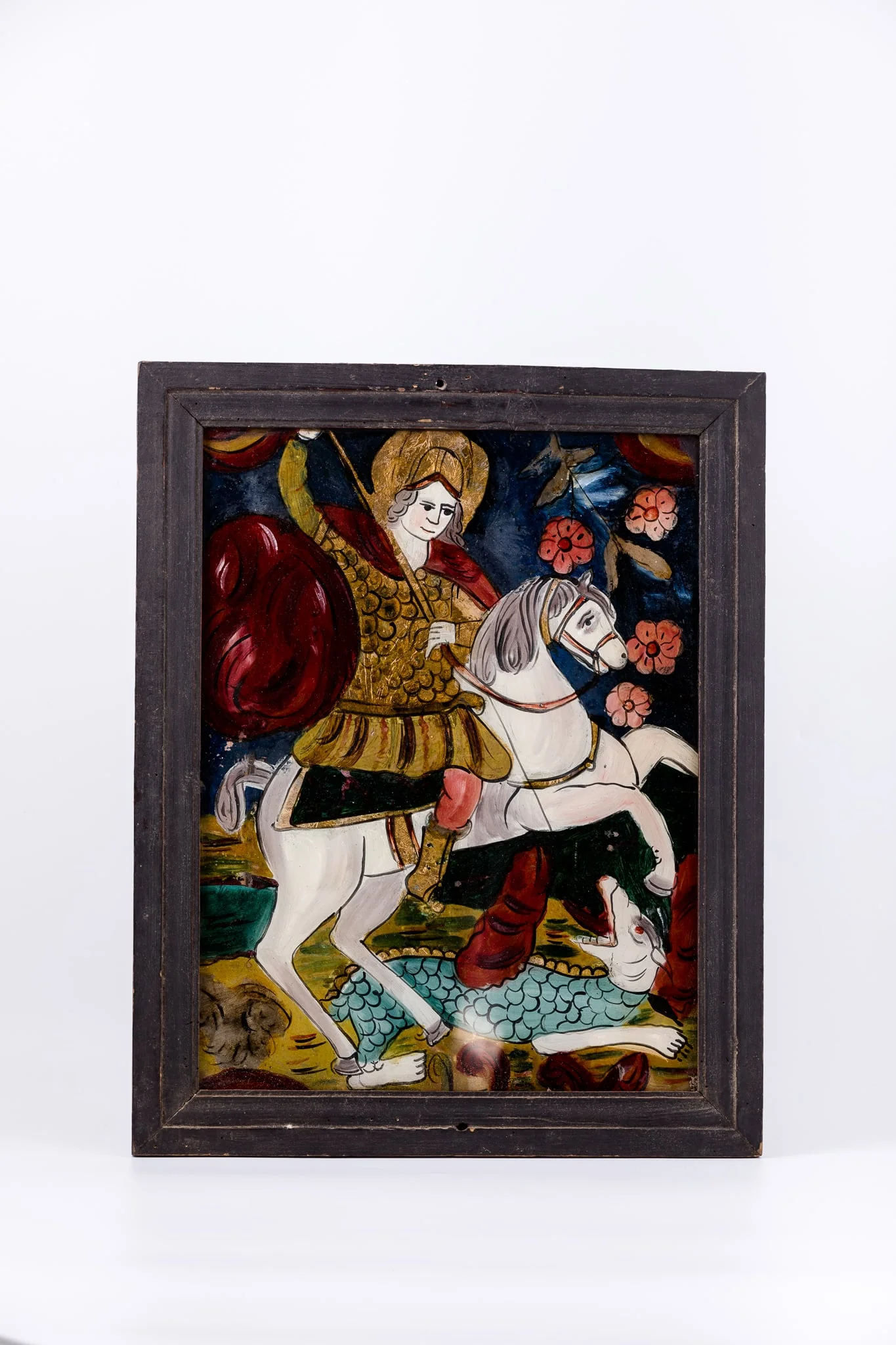 Sfântul Mare Mucenic Gheorghe este așezat călare pe un cal alb cu șa neagră, omorând balaurul alb-albastru-gri cu creastă roșie-acajou, solzi și coadă lungă, cu lancea, pe care o ține cu amândouă mâinile, înfingându-i-o animalului în gâtlej. Fondul este cerul albastru ultramarin bleumarin în registrul superior. În registrul inferior, fondul este brun-ocru și albastru cobalt, cu linii ondulatorii verzi, cele două registre în centrul icoanei ușor întrepătrundu-se. Mantia Sfântulu Mucenic Purtător de Biruință este roșie-vișinie stacojie, având cămașa de cavaler cu zale. Culoarea roșie este caracteristică mucenicilor și martirilor. Cerul albastru este acoperit cu elemente fitomorfe - flori de măr roz-roșii. Icoana, fiind din Mărginimea Sibiului, are desenul mai neglijent, cromatica puternică, fauvistă. Cromatica este armonioasă: roșu vișiniu-stacojiu, albastru, bleu-ultramarin bleumarin, roz, brun, galben-ocru, gri, alb, negru. Icoana este din Mărginimea Sibiului.