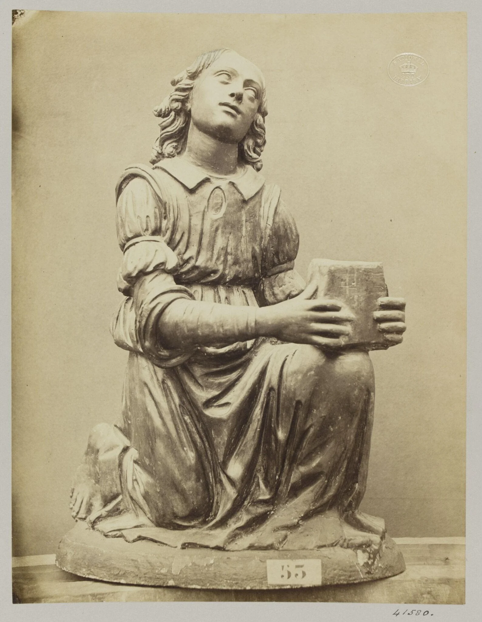Figure of an angel on her knees in red terra cotta