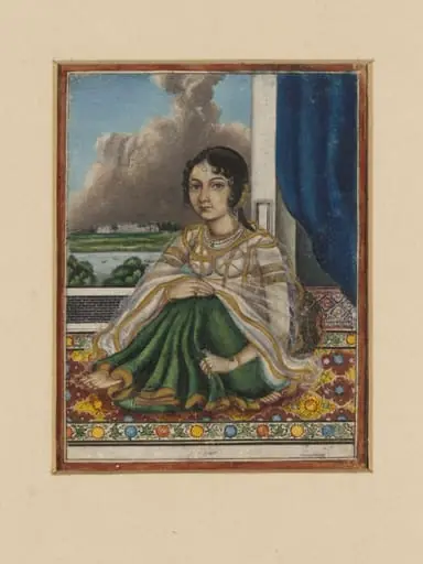 An Indian lady seated on a carpet by an open door overlooking a river with a European-style house on the opposite bank.