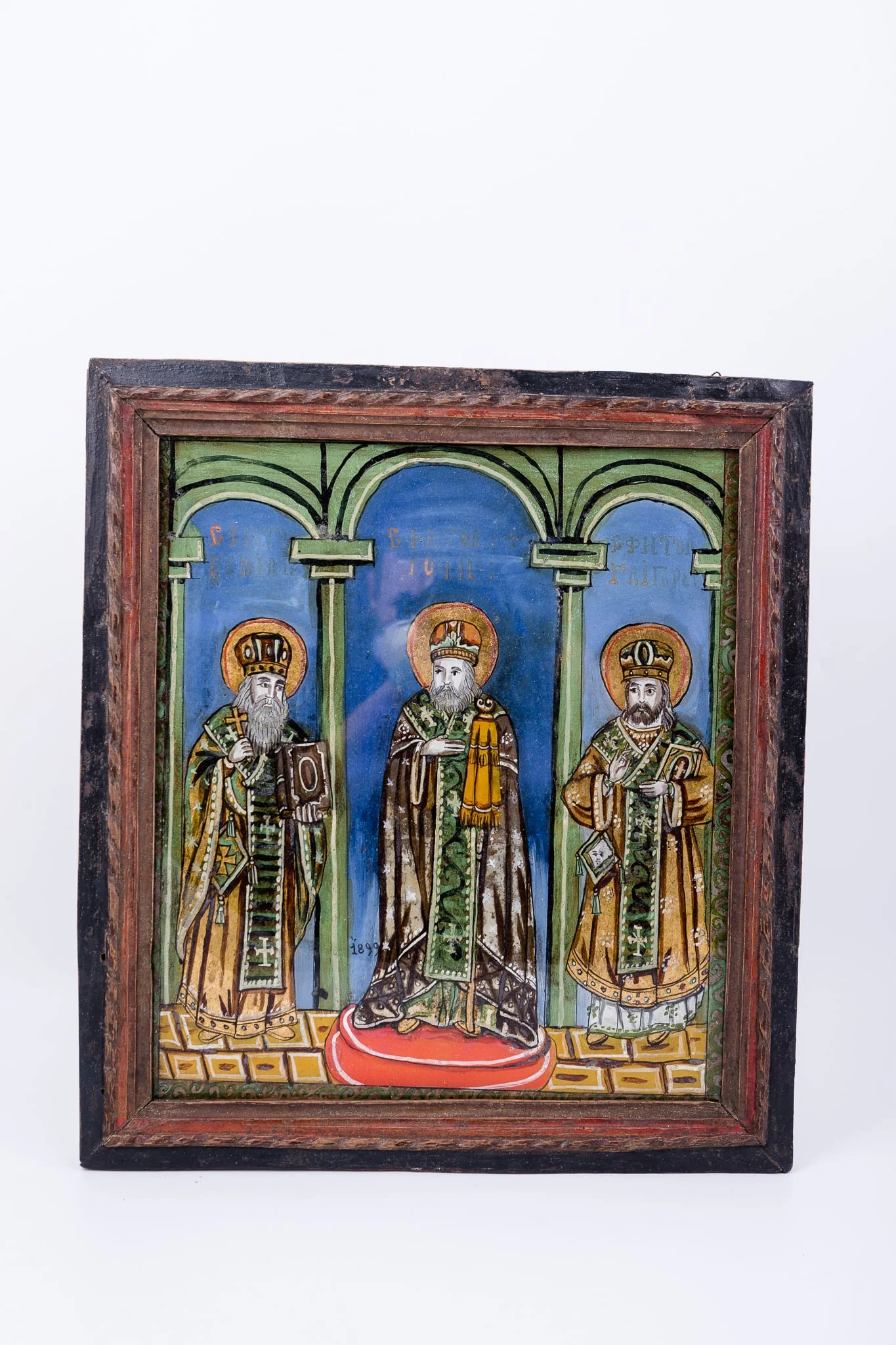 Cei Trei Sfinți Ierarhi Vasile cel Mare, Grigorie de Dumnezeu Cuvântătorul și Ioan Gură-de-Aur slujesc și săvârșesc Sfânta Liturghie împreună. Sunt înveșmântați în veșminte liturgice: sacos, felon și epitrahil verde, brun-ocru, kaki, brun-bronziu cu câte patru cruci pe mijlocul patrafirului. Sfântul Vasile cel Mare binecuvântează cu crucea în mâna dreaptă și ține în mâna stângă Sfânta Evanghelie. Sfântul Ioan Gură-de-Aur este în mijloc, așezat cu picioarele pe o pernă rotundă roșie, are mâna dreaptă lipită la piept, în semn de evlavie și cu mâna stângă ține cârja arhierească, Sfântul Grigorie binecuvântează cu mâna dreaptă și ține în mâna stângă Sfânta Evanghelie. Fondul este albastru ceruleum în registrul superior, în registrul inferior este un caroiaj brun-ocru-galben chihlimbar. Cromatica este armonioasă și săracă în nuanțe: verde smarald, absint, kaki, alb, roșu vermillon, albastru, alb, negru. Este o icoană specifică picturii de Valea Sebeșului, cu un desen fin cu conturul negru și cromatica pastelată. Inscripția din româno-chirilică se traduce Sfântul Vasile Sfântul Ioan Sfântul Grigorie., by Unknown, 1899