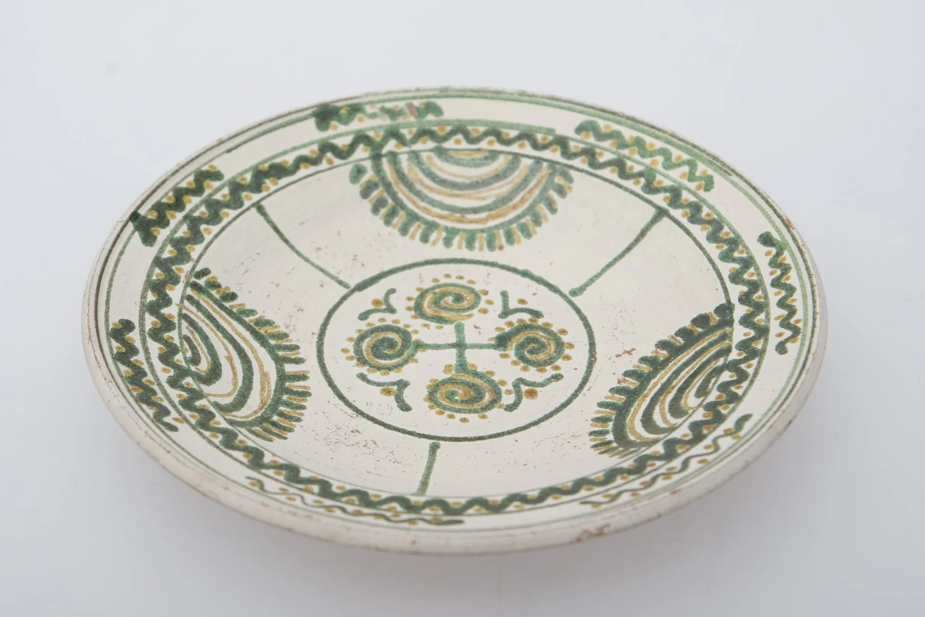 Vas ceramic de formă circulară și profil tronconic. Fața farfuriei a fost introdusă în angobă albă. Decorația a fost făcută cu pensula. Pe fundul farfuriei un cerc circumscris patru motive în spirală. Pereții farfuriei, au fost împărțiți în trei părți egale, pe circumferință, delimitate fiecare parte de o linie verticală, motivul bradului este reprezentat printr-o succesiune de semicercuri, pe ultima dintre ele pictându-se "țepii" bradului. Buza farfuriei a fost împărțită în două registre, în primul fiind pictat valul continuu, a doua cu val întrerupt. Pe fundul vasului, la spate, ștanțat ”D. Șchiopu C. Vlădești 1980'' înscris într-un cerc. Pe inelul de susținere dispuse două orifficii pentru atârnare. Cromatică: fond de angobă albă; motive: smalț verde și maro., by Șchiopu Dumitru