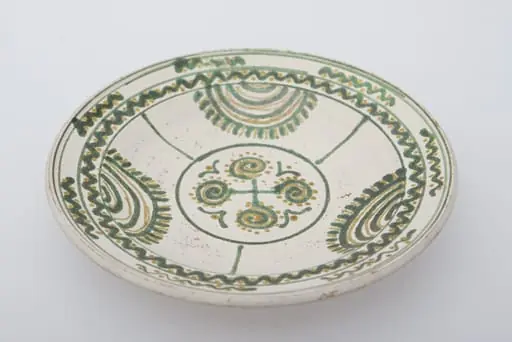 Vas ceramic de formă circulară și profil tronconic. Fața farfuriei a fost introdusă în angobă albă. Decorația a fost făcută cu pensula. Pe fundul farfuriei un cerc circumscris patru motive în spirală. Pereții farfuriei, au fost împărțiți în trei părți egale, pe circumferință, delimitate fiecare parte de o linie verticală, motivul bradului este reprezentat printr-o succesiune de semicercuri, pe ultima dintre ele pictându-se "țepii" bradului. Buza farfuriei a fost împărțită în două registre, în primul fiind pictat valul continuu, a doua cu val întrerupt. Pe fundul vasului, la spate, ștanțat ”D. Șchiopu C. Vlădești 1980'' înscris într-un cerc. Pe inelul de susținere dispuse două orifficii pentru atârnare. Cromatică: fond de angobă albă; motive: smalț verde și maro.