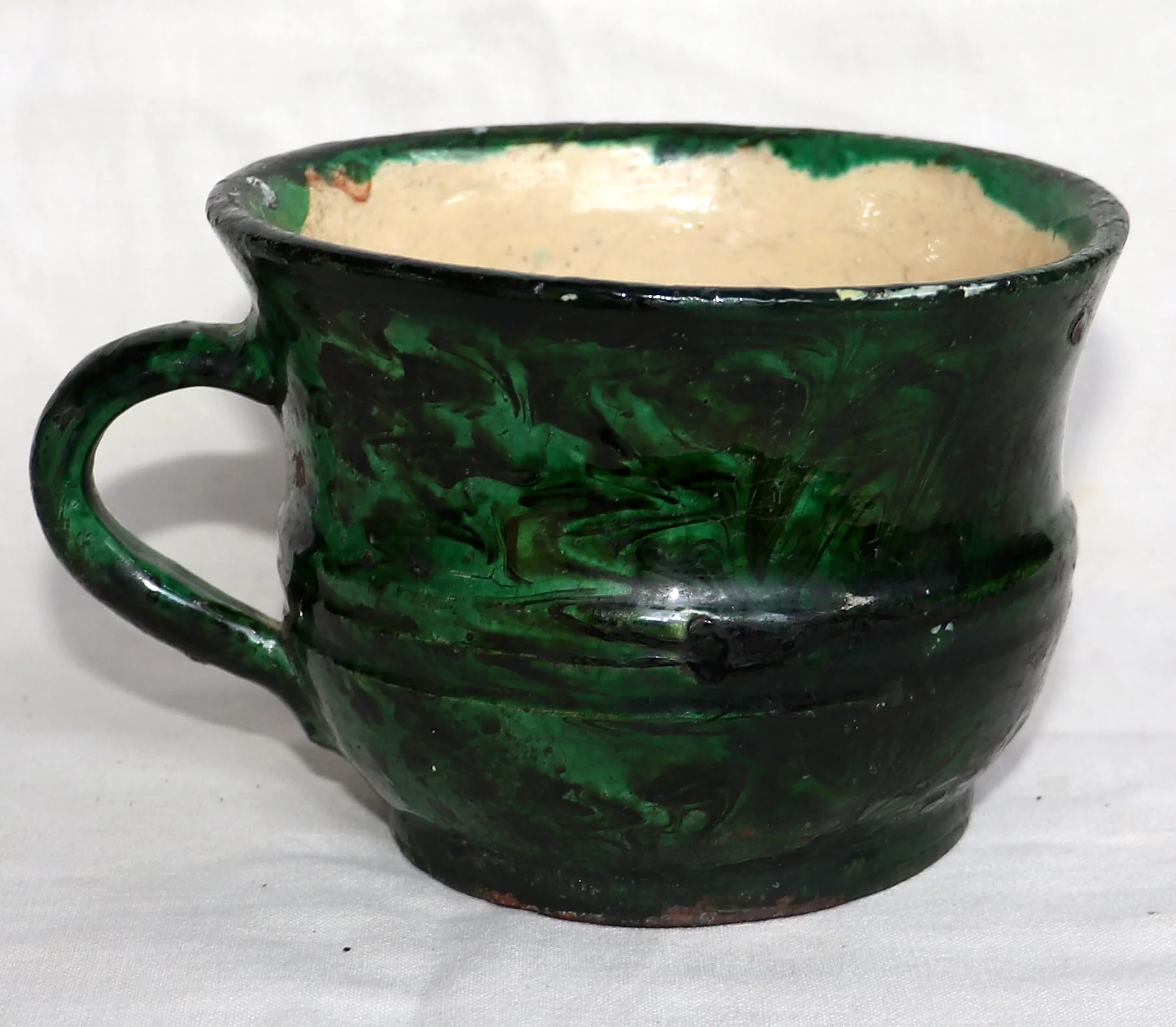 Piesa are o formă cilindrică, fiind lărgită în partea superioară și îngustată către bază. Are toartă situată în zona centrală a suprafeței. Este smălțuită și decorată cu motive geometrice: pe toată suprafața se găsesc forme geometrice (mai ascuțite și mai rotunjite), neregulate, realizate cu pensula; asemenea și toarta. La mijlocul cănii (în partea exterioară) se găsesc două cercuri incizate de jur-împrejur, acestea fiind singurele motive ornamentale ale obiectului. Culorile folosite pentru decorarea ulcelei sunt verde și negru, la interior piesa fiind de culoare bej (crem); fundul nu este smălțuit, culoarea fiind cea cărămizie., by olar