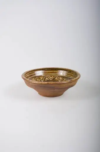 Recipient tronconic, cu gura mai largă decât baza, cu buza dreaptă și înaltă. Acesta este smălțuit doar la interior. Vasul este decorat prin pictare cu cornul, cu ornamente geometrice: spirală pe fund, linii circulare, linii vălurite și ”V”-uri înscrise pe pereți și decorații de tip val pe margine. Din punct de vedere al cromaticii, se observă un fond ocru la interior, cărămiziu la exterior, motivele fiind pictate cu alb.