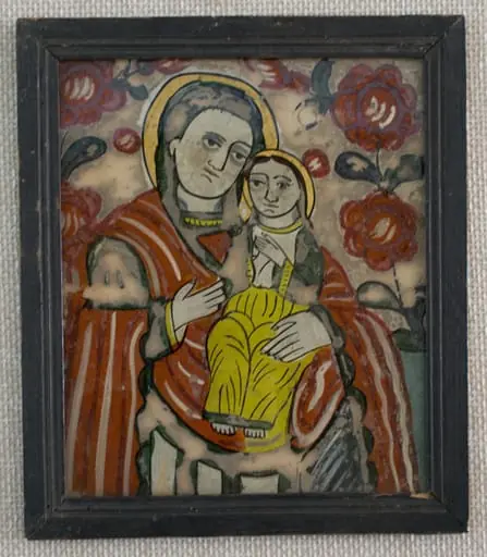 Icoana o reprezintă pe Maica Domnului cu Pruncul, tipul Hodighitria(Arătătoarea Căii). Cu mâna stângă susține Pruncul, cu dreapta arată către El. Maica are părul acoperit cu un văl verde.Veșmintele multicolore,(specific fazei de decadență a picturii de icoane pe sticlă)-roșu-mantia, cămașă, albă vrâstată cu verde, mâneci verzi, borduri diverse. Chipul cu umbre gri deschis, bărbia groasă, buze subțiri. Pruncul, cu amândouă mâinile la piept, are părul lung, castaniu și fața feminină. Aureolele sunt diforme, umplute cu bronz auriu. Câmp alb murdar decorat cu două ramuri cu flori roșii și boboci(ruje) care se unesc deasupra capului Maicii - 3/4 superior, bleu(1/4 inferior).Cromatica este dominată de roșu culorile stridente :alb, bleu, roșu, verde închis, ocru galben, brun, negru. Icoana are trăsăturile specifice picturii târzii din zona Nicula -Gherla: supraabundența detaliului, a decorului vegetal, apariția bronzului în locul foiței de aur, câmpul bicolor, sticla de proveniență industrială. Rama profilată este vopsită cu negru și încheiată oblic;dosul este din lemn subțire de brad;