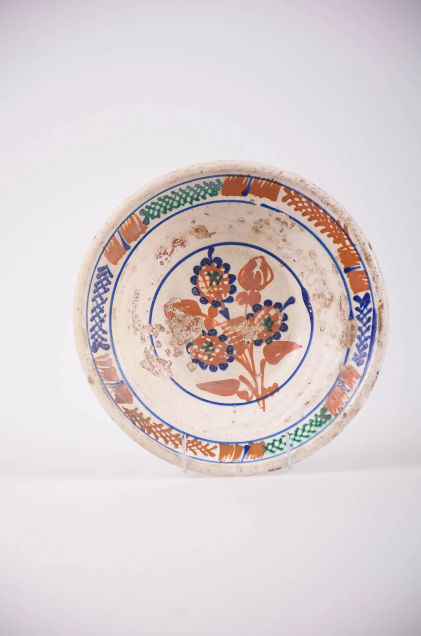 Farfurie de formă tronconică cu deschidere mare. Smălțuit în interior și ornamentat cu motive geometrice: cercuri; motive florale, pete de culoare și motiv vegetal: brăduț. Motivul floral se află pe fundul vasului și este înscris într-un cerc. Motivele vegetale și petele de culoare sunt amplasate pe marginea farfuriei și sunt încadrate de două cercuri. Cromatică: fond: alb; motive: maro; verde; albastru., by Unknown, 1850