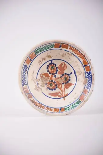Farfurie de formă tronconică cu deschidere mare. Smălțuit în interior și ornamentat cu motive geometrice: cercuri; motive florale, pete de culoare și motiv vegetal: brăduț. Motivul floral se află pe fundul vasului și este înscris într-un cerc. Motivele vegetale și petele de culoare sunt amplasate pe marginea farfuriei și sunt încadrate de două cercuri. Cromatică: fond: alb; motive: maro; verde; albastru.