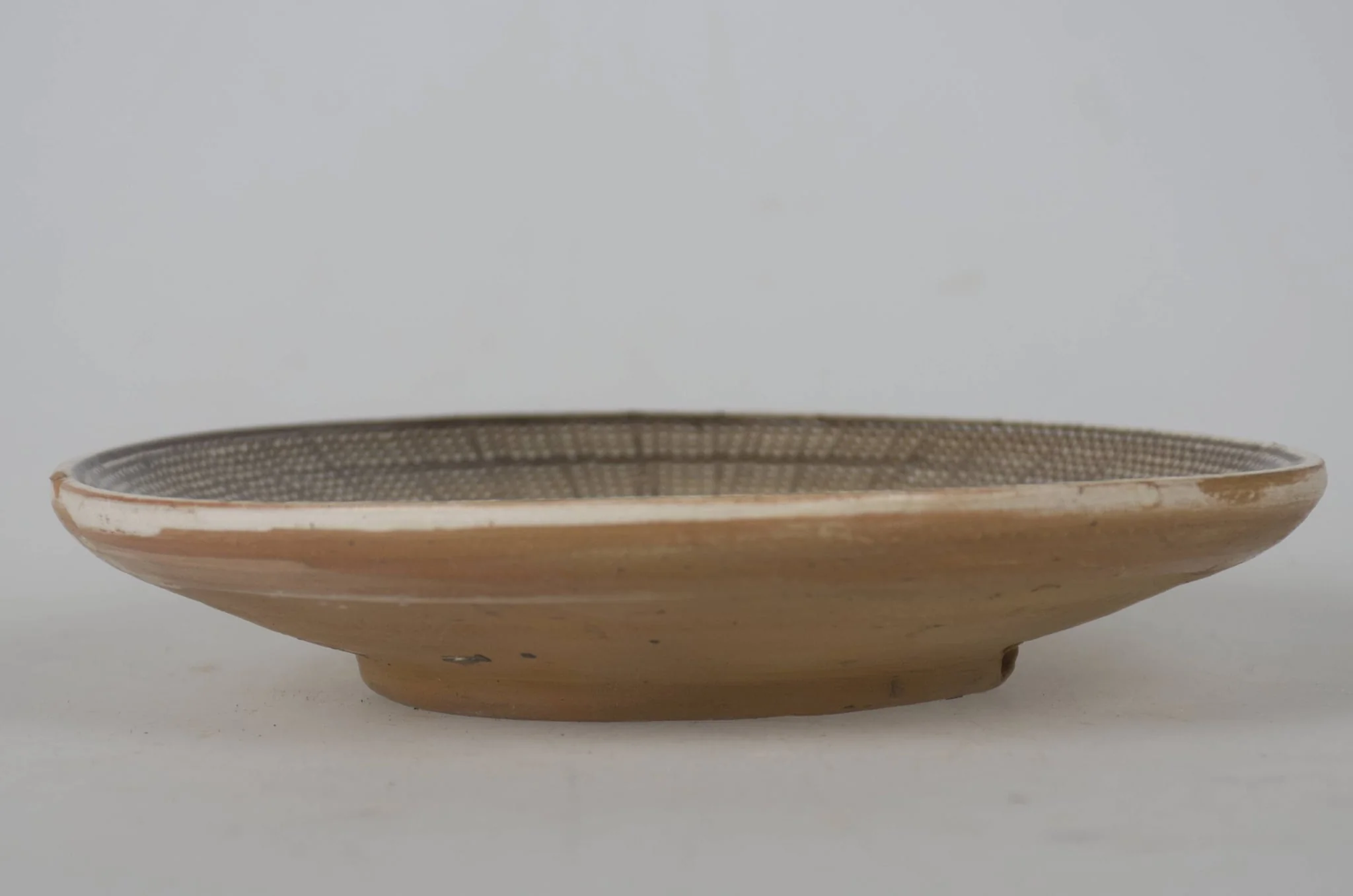 Vas ceramic smălțuit de mici dimensiuni, modelat la roata olarului, uscat, pictat, ars de două ori și smălțuit. Taierul prezintă o bază plată din care pornesc pereții foarte evazați/arcuiți cu buza ridicată. Decorul este dispus pe toată suprafața vasului, care în prealabil a fost angobat. Fundul vasului este nedecorat; în zona de demarcarea dintre fundul vasului și pereți un registru jirăvit, cuprins între două linii de culoare maro-roșcat. Un al doilea registru realizat din frunze de culoare verde, maro-roșcat și maro-închis. Marginea vasului a fost jirăvită, realizată cu „gaița”. Cromatica vasului este alb la interior și maro-deschis la exterior, iar cea a decorului pictat este maro-închis; verde; maro-roșcat; alb., by Ogrezeanu Stelian, unspecified