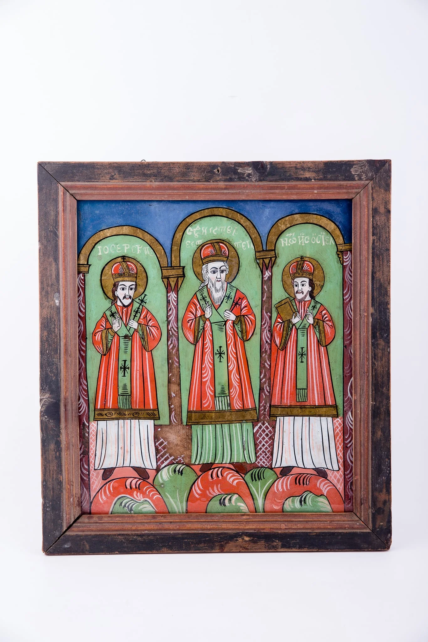 Cei Trei Sfinți Ierarhi Vasile cel Mare, Grigorie de Dumnezeu Cuvântătorul și Ioan Gură-de-Aur slujesc și săvârșesc Sfânta Liturghie împreună. Sunt înveșmântați în veșminte liturgice: sacos verde-alb-verde, felon roșu vermillon, epitrahil verde cu câte patru cruci. Sfântul Vasile cel Mare are Sfânta Evanghelie în mâna dreaptă. Sfântul Ierarh Grigorie de Dumnezeu Cuvântătorul Binecuvintează. Cei trei Sfinți Ierarhi stau cu picioarele pe perinițe rotunde de culori alternative: roșu, verde, alb. Fiecare sfânt ierarh este încadrat de două coloane și o boltă de biserică. Sunt prezente elemente arhitectură bisericească. Fondul registrului superior este albastru. Cromatica este luminoasă și armonioasă: verde, alb, roșu vermillon, roșu, albastru, negru. Este o icoană specifică picturii de Țara Făgărașului, cu un desen fin cu conturul negru și cromatica pastelată. După stilul picturii întregii compoziții, icoane poate să aparțină lui Matei Țimforea.