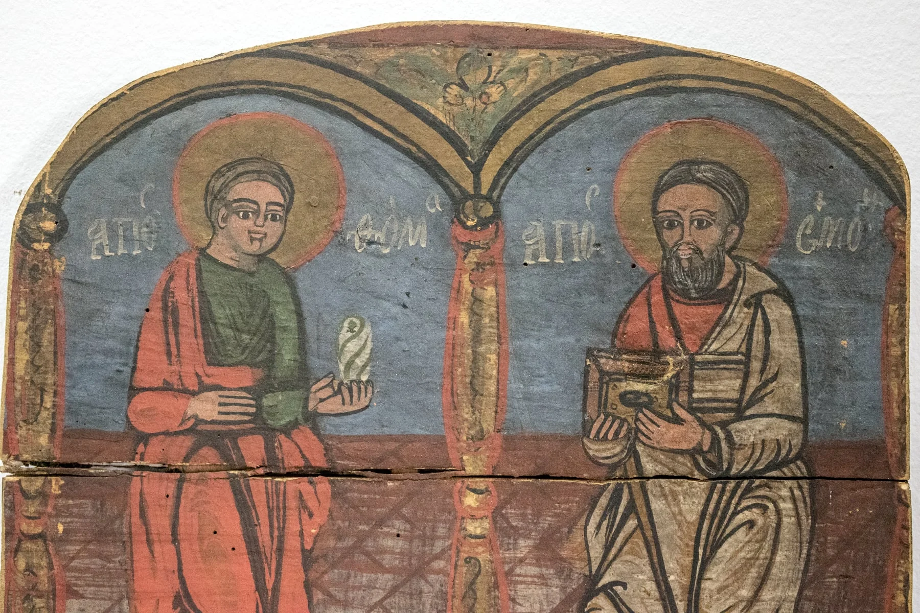 Cei doi apostoli sunt redați într-o manieră naivă, populară. Apostolul Toma(stânga) și apostolul Simion sub încadrați de câte un portal semicircular cu decor fitomorf, cadrele fiind separate de stâlpii fusiformi decorați cu motivul funiei. Ambii apostoli sunt desculți, înveșmântați simplu(Toma chiton verde, himation roșu, Simon chiton roșu, himation alb). Apostolul Toma este redat tânăr, fără barbă, ținând în mână un rotulus, Simon cu barbă căruntă, în mână cu o carte. Fețele expresive, carnația roz, proporțiile respectate, dar se observă stângăcii. Fond: în partea de jos, pardoseala din dale de piatră, sus albastru de Prusia, inscripții prescurtate cu majuscule de culoare albă.