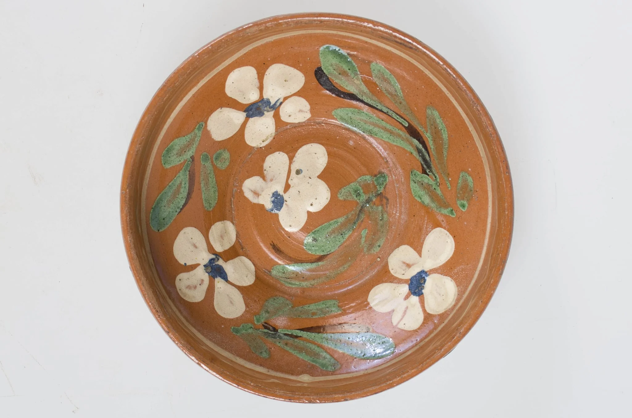 Blidul de formă tronconică adânc, smălțuit (la interior). Acesta este ornamentat cu motive florale, având cu buza înaltă. Blidul este neornamentat la exterior, fiind smălțuit (la exterior) doar pe buză. Pe exteriorul buzei este incizată o linie. Fundul obiectului are formă circulară, fiind prevăzut cu două orificii pentru prindere. Cromatică: fond: cărămiziu (exterior); alb (interior); decor: verde; alb; albastru; maro., by Unknown, 1850