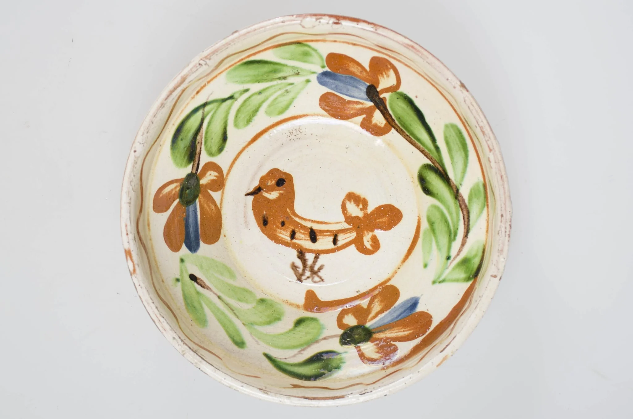 Blid de formă tronconică cu buza înaltă, smălțuit pe interior. Acesta este ornamentat cu motive florale, avimorfe, liniare și curbilinii, realizate prin pictare cu pensula. Pe buza interioară a vasului se identifică motivul geometric al liniei vălurite succedat de motive curbilinii care încadrează un registru floral-vegetal continuu dispus pe zona mediană a vasului. De asemenea, se identifică un motiv avimorf pictat pe fundul vasului și încadrat de un cerc. Obiectul este smălțuit la exterior doar pe buză, pe exteriorul buzei fiind incizate două linii. Fundul este inelar, prevăzut cu două orificii pentru agățare. Se identifică scurgeri insulare de smalț pe exteriorul buzei. Pe exterior se profilează, în zona diametrului maxim, un brâu continuu obținut prin lucrarea la roată. Cromatică: fond: alb (la interior); cărămiziu (exterior); motive: cărămiziu; verde; maro; albastru., by Unknown, 1850