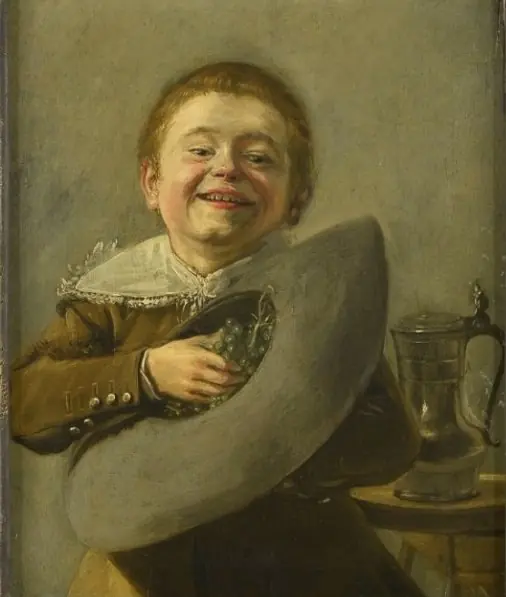 Smiling boy holding grapes in his hat