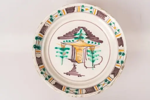 Farfurie semi-adâncă, cu buza răsfrântă. Decorul, dispus prin pictare pe un fond alb lăptos, este format dintr-un motiv arhitectural și motive vegetale stilizate, dispuse central, pe fundul farfuriei, și motive geometrice (linii galbene și dungi maro paralele, grupuri de linii intersectate sub formă de X, decorate cu puncte verzi și galbene), dispuse pe buza farfuriei, într-un registru continuu. Cele două registre ornamentale, cel central de pe fundul farfuriei și cel marginal, de pe buza acesteia, sunt încadrate în cercuri formate din linii fine de culoare maro-brun. Cromatica: alb, verde, maro-brun, galben ocru.