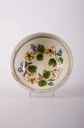 Farfurie de formă tronconică, adâncită, cu buza foarte înaltă; pe fund are găuri pentru agățare. Este smălțuit în interior și exterior (buza). Decorat cu motive geometrice: linie; motive fitomorfe; motive florale. Cromatică: fond: alb; motive: verde; maro; albastru.