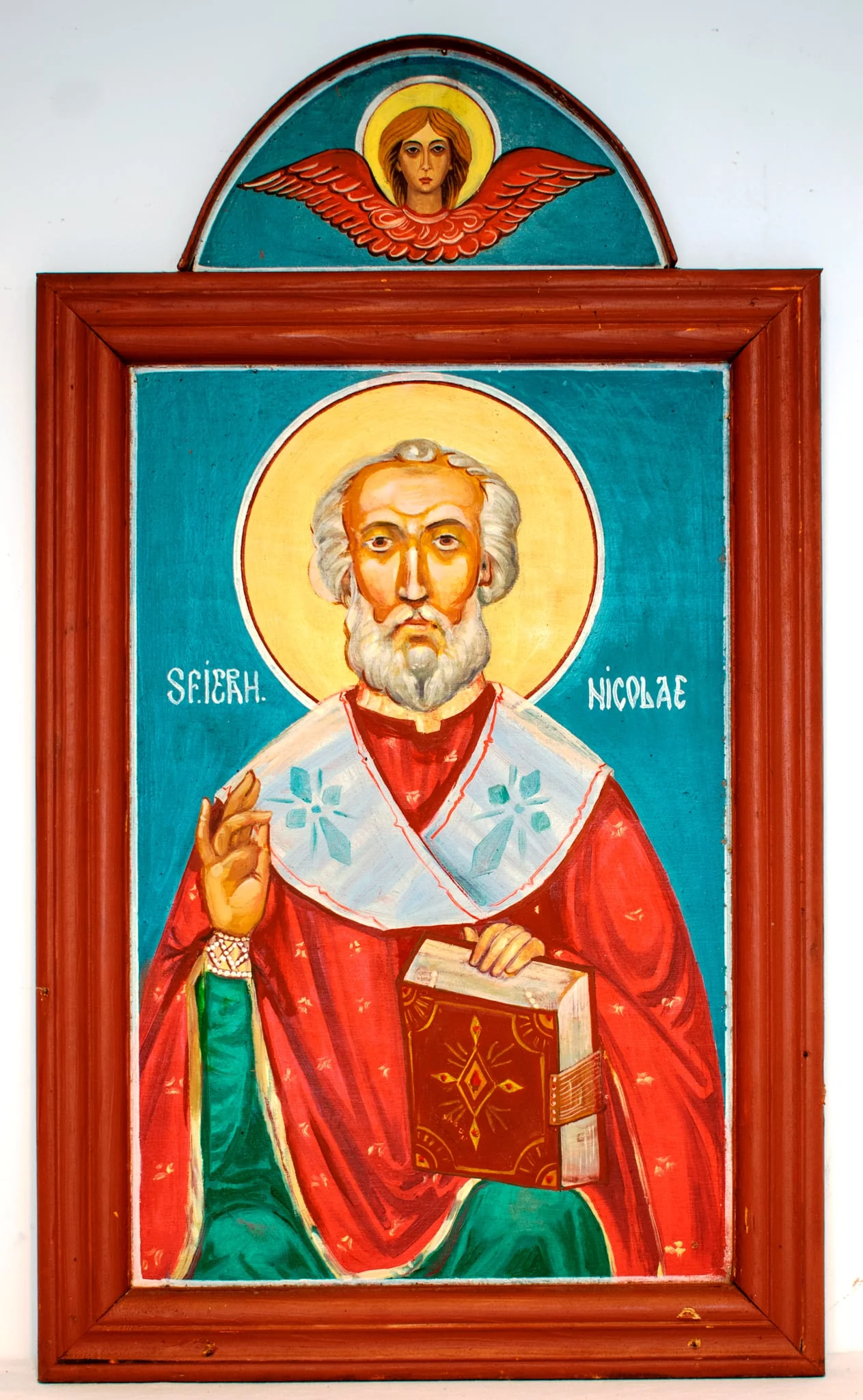 Sfântul ierarh Nicolae este redat 3/4, așezat. Binecuvântând cu mâna dreaptă, cu stânga sprijinind o Evanghelie pe genunchi. Pictat cu capul decoperit, fruntea înaltă, figura sobră, expresivă, bine proporționată. Părul și barba albe, scurte, ondulate. Ochii căprui, nasul drept.Înveșmântat cu sacos roșu decorat cu motive florale miniaturale, stihar verde cu mânecuțe brodate cu perle, epitrahil alb cu cruci gri. În jurul capului aureolă de culoare galbenă, cu chenar dublu(roșu și alb). Evanghelia este legată în piele, cu coperta decorată cu motive geometrice pe fond cafeniu. Fond bleu închis, cu o linie de chenar albă, subțire, la fel cu inscripția scrisă în dreptul umerilor. Paleta cromatică este variată, dar nu foarte armonioasă, culorile reci. Pictura este realizată de un pictor contemporan cu școală, autorul picturii unor biserici și icoane. Rama profilată, lată, alcătuită din patru stinghii îmbinate oblic la colțuri, bătută în cuie metalice, culoare brun roșcat. În partea de sus este adăugată o porțiune semicirculară, cu margine din placaj îngust, montat transversal. Pe fondul bleu închis al acesteia este pictat un heruvim cu aripile întinse, chip sobru, cu păr blond, ochi negri gura roșie. În partea de jos sunt două cuie mari de fier cu care era fixată., by Țiurea Gheorghe?