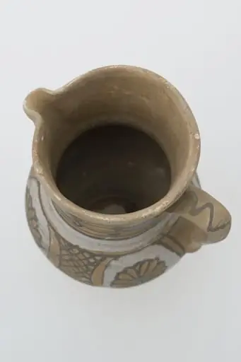Cană de vin de formă bitronconică cu gâtul lung și buză dreaptă cu cioc. Registrele ornamentale se succed de jos în sus, delimitate de cercuri concentrice, și prezintă pe corpul vasului motive florale și geometrice sub formă de hașură întrerupte de partea de sus de o zonă cerc alb mai gros și mai apoi continuat cu cercuri concentrice ce delimitează de mijloc și de sub buză două cercuri albe groase (angoba). Cromatică: fond: alb; cărămiziu; motive: maro; gri; albastru.