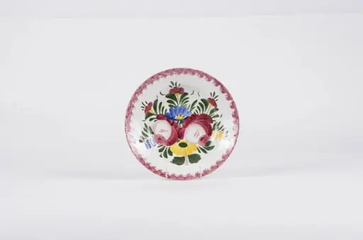 Vasul este de formă tronconică fiind smălțuit interior-exterior. Este confecționat din faianță Decorul este format din motive florale pictate pe fond alb; gura este decorată în stropi de culoare vișinie iar baza farfuriei este decorată cu motive florale. Se identifică șapte flori alcătuind motivul decorativ pe baza farfuriei. Pe spate inscripția este indescifrabilă. Cromatică: galben; albastru; verde; vișiniu; alb;
