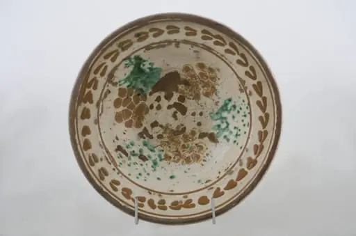 Vas ceramic de formă tronconică cu baza plată, pereții larg evazați și buza dreaptă și înălțată. După modelarea la roată, uscarea și arderea recipientului, a fost aplicat un strat de angobă în interiorul vasului, peste care a fost pictat decorul floral și vegetal stilizat, format din două registre. Primul registru, situat pe fundul și pereții vasului, și încadrat de o linie circulară, a fost decorat cu câte trei pete mari de culoare verde și galben-muștar, realizate prin stropire cu pensula. Al doilea registru, cel care decorează buza recipientului ceramic și este mărginit, la rândul lui de o linie circulară, prezintă elemente ornamentale de tipul „bobului de grâu”. Cromatică: fond: alb; motive: roșu; albastru; verde.