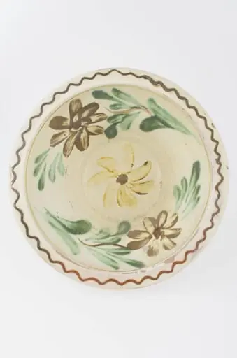 Farfuria este adâncită, tronconică cu buza profilată și pereți înalți. Este smalțuită pe interior, având dispuse elementele decorative atât pe buza vasului (motive geometrice) cât și pe pereții interiori după cum urmează: central o floare galbenă încadrată de alte două flori cu frunze - una maro și cealaltă galbenă. Cromatică: fond: alb-gălbui; motive: brun; verde; galben.