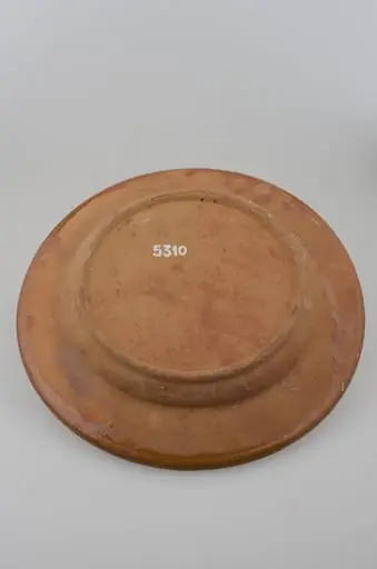 Blid tronconic cu fund plat, margine puțin ridicată și buza ușor oblică. Decor cu motive aviforme și florale: cocoș pe centru și o floare; pe margine, circular, motive geometrice (semicercuri, liniare, punctate, zig-zag). Cromatică: fond: cărămiziu; motive: maro; verde; alb; galben.