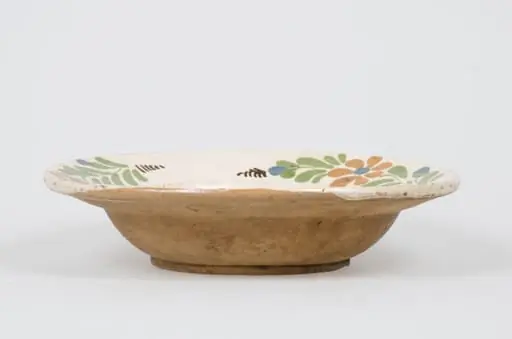 Vas de formă tronconică, adâncit smălțuit în interior. Acesta este decorat pe margine cu motive vegetale și florale pe un registru dispus în zona diametrului maxim. Cromatică: fond cărămiziu (exterior); fond alb (interior); verde; maro; albastru.