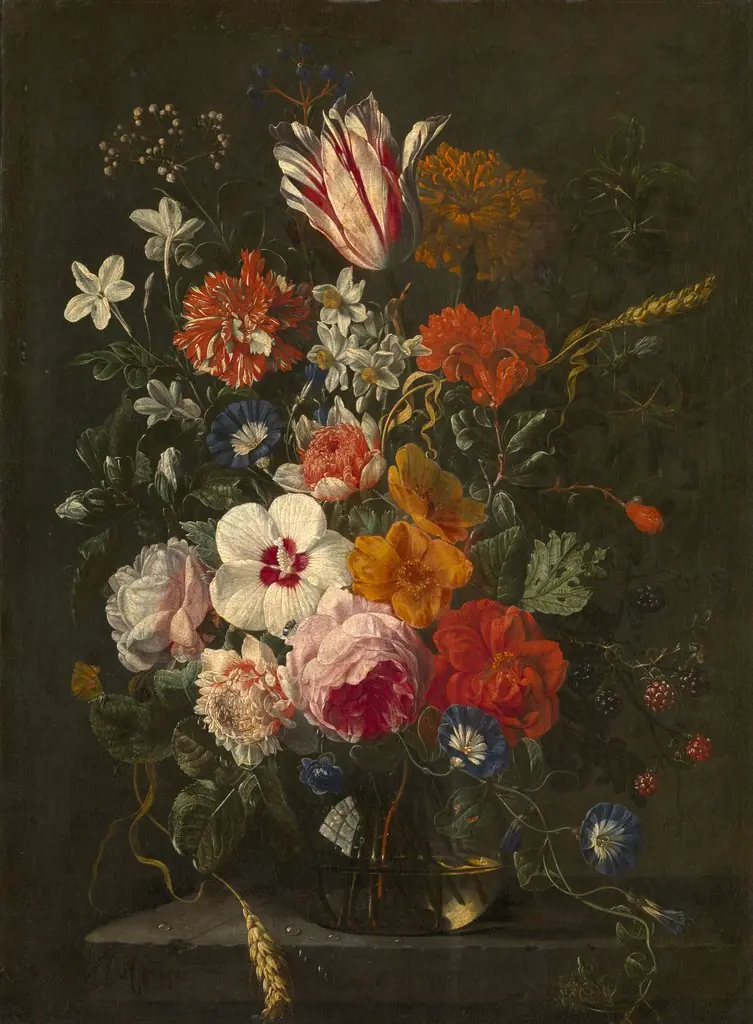Flowers and a branch of berries in a glass vase on a stone ledge
