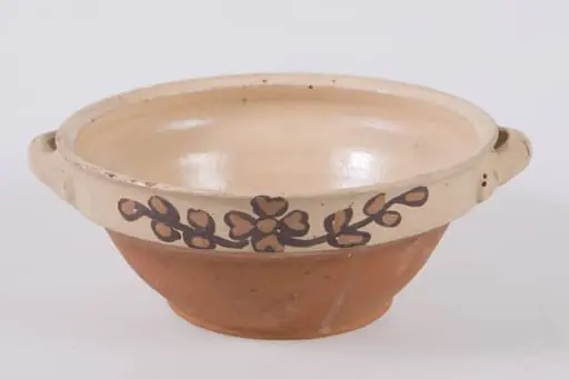 Castron mic de formă tronconică, cu baza marcată printr-un inel proeminent. Buză cu contur rotund în exterior și ascuțit în interior. Decorul floral ce constă dintr-o floare pictată cu cornul în interior, pe fundul vasului. Cromatică: fond: alb-crem; motive: galben; negru; verde.