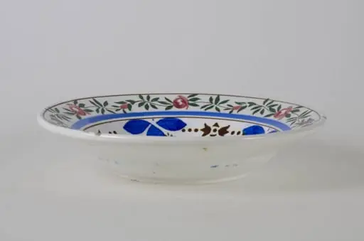 Farfurie de formă tronconică, adâncită; este decorată cu motive florale pe toată suprafața; florile de pe margine sunt încadrate de trei cercuri concentrice dintre care una spre exterior și două spre interior; cromatică: fond alb, motive: roșu; verde; albastru; maro; galben. Pe fund are o ștanță: trei cercuri concentrice. Tot pe fundul vasului sunt două incizii în care este introdus un șnur folosit la agățarea vasului pe perete.