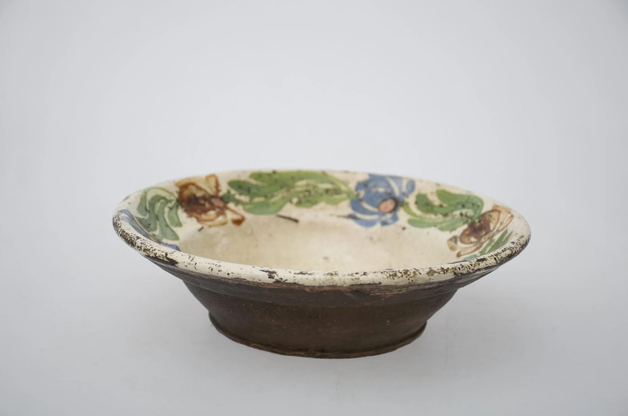 Farfurie de formă tronconică adâncă cu buza largă și decor pe fund, spre margini. Ornamentat cu motive florale. Cromatică: fond: alb; motive: maro; verde; albastru., by Unknown, 1850