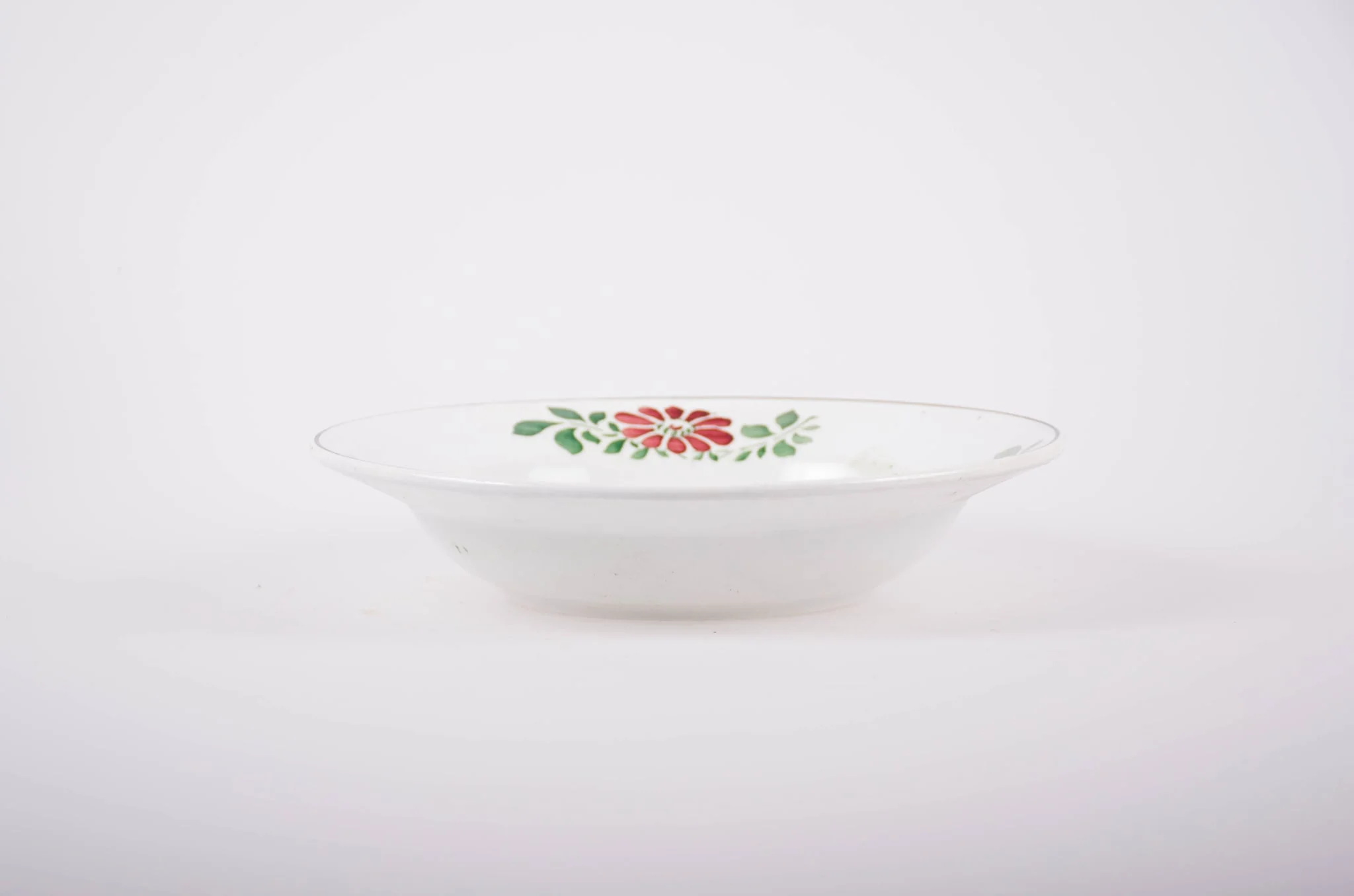 Farfurie de porțelan de formă tronconică, smălțuită în interior și la exterior. Pe fond alb avem flori stilizate (margarete). Buza farfuriei este conturată de o dungă neagră, iar pe margini sunt flori vișinii cu frunze verzi; în interiorul farfuriei pictate avem două flori mari (vișinii) și frunze verzi., by Unknown, 1850