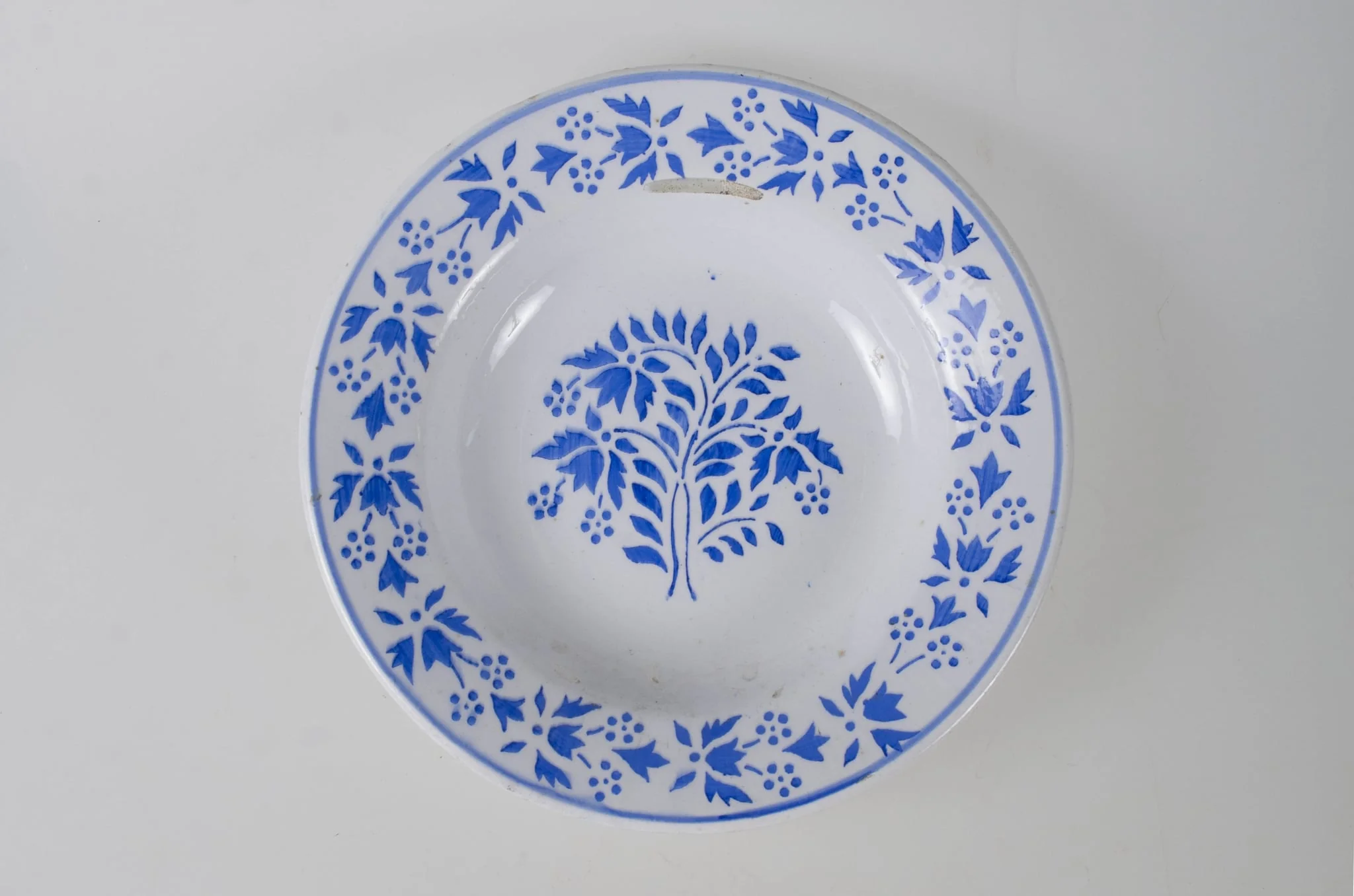 Farfuria are formă tronconică ușor adâncită. Pe buza vasului se identifică un registru decorativ floral, vegetal, continuu mărginit de o linie. Pe fund este o ștanță: o casă cu o pasăre pe acoperiș. Pe fundul vasului sunt două incizii în care este introdus șnurul folosit la agățarea vasului pe perete. Cromatică: fond: alb; motive: albastru., by Unknown, 1850