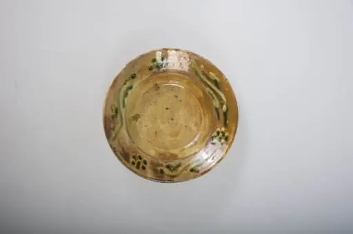 Blid de formă tronconică, adâncit cu margini puțin ridicate. Decorul este format din ornamente florale și vegetale stilizate, amplasate pe margini, buză. Blidul este smălțuit la interior și la exterior. Cromatică: maro; galben; verde.