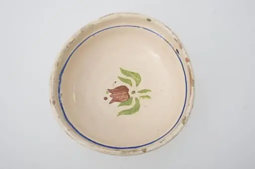 Blid de formă tronconică, adâncită; este smălțuit interior și exterior (doar buza); este decorat cu motive geometrice pe margine: linie; în centru este decorat cu motive florale: lalea. Cromatică: fond crem, maro, verde, albastru.