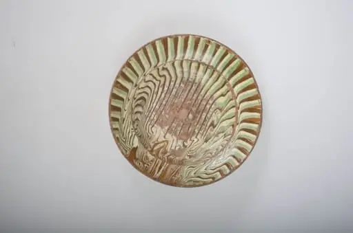Vas de formă tronconică cu buza largă, smălțuită, cu decor amplasat pe toată suprafața, format din motive geometrice: liniar și curbiliniu. Cromatică: ocru; alb; verde.