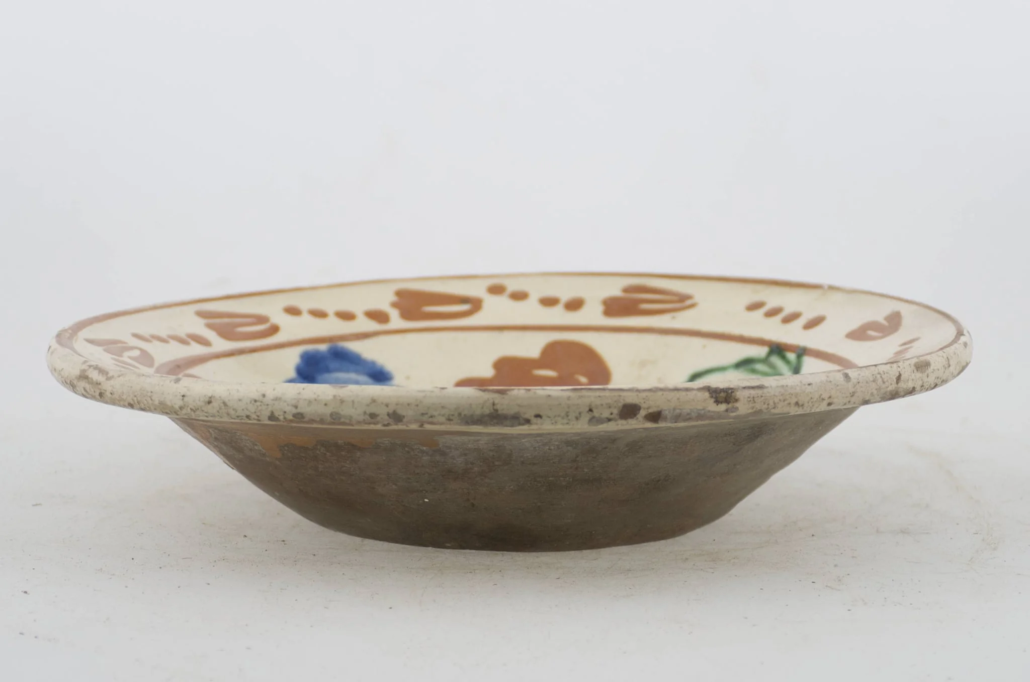 Vas ceramic de formă tronconică cu baza plată, pereții larg evazați și buza profilată. După modelarea la roată, uscarea și arderea recipientului, a fost aplicat un strat de angobă în interiorul vasului, peste care a fost pictat decorul floral și vegetal stilizat, format din două registre. Primul registru, situat pe fundul și pereții vasului, și încadrat de o linie circulară, a fost decorat cu motive florale stilizate: pe fundul vasului se află o floare, cu petalele de diferite culori. Pereții recipientului ceramic au fost decorați la rândul lor cu opt flori, dispuse concentric. Al doilea registru, cel care decorează buza recipientului ceramic, și este mărginit la rândul lui de o linie circulară, prezintă un brâu compus din nouă flori cu tulpinile formate din patru puncte. Cromatică: alb la interior; cărămiziu la exterior; motive: albastru; verde; maro-roșcat., by Unknown, unspecified, 1850