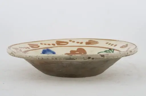 Vas ceramic de formă tronconică cu baza plată, pereții larg evazați și buza profilată. După modelarea la roată, uscarea și arderea recipientului, a fost aplicat un strat de angobă în interiorul vasului, peste care a fost pictat decorul floral și vegetal stilizat, format din două registre. Primul registru, situat pe fundul și pereții vasului, și încadrat de o linie circulară, a fost decorat cu motive florale stilizate: pe fundul vasului se află o floare, cu petalele de diferite culori. Pereții recipientului ceramic au fost decorați la rândul lor cu opt flori, dispuse concentric. Al doilea registru, cel care decorează buza recipientului ceramic, și este mărginit la rândul lui de o linie circulară, prezintă un brâu compus din nouă flori cu tulpinile formate din patru puncte. Cromatică: alb la interior; cărămiziu la exterior; motive: albastru; verde; maro-roșcat.