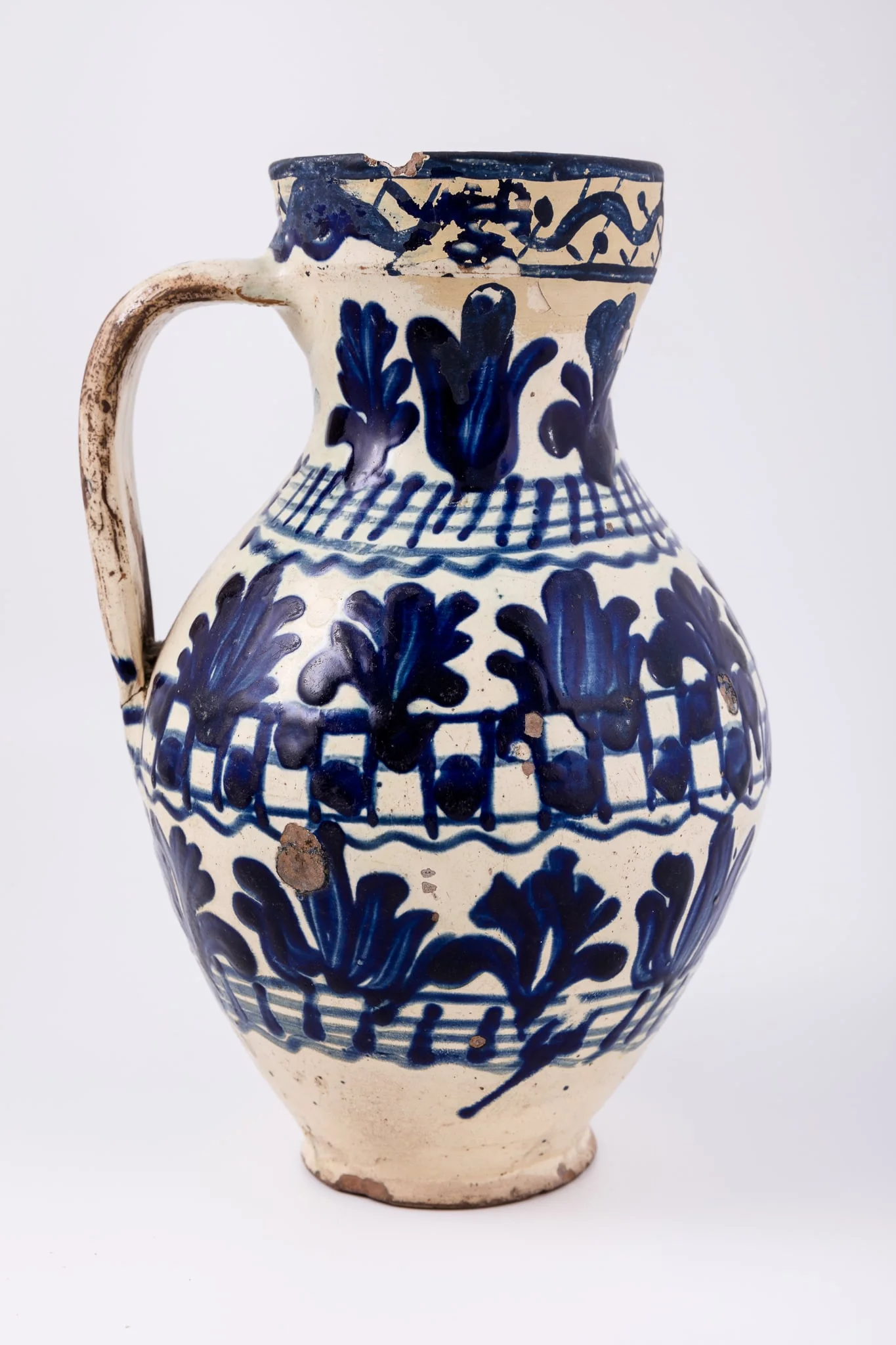 Cană piriformă prevăzută cu o toartă dreaptă și lată, gura rotundă. Suprafața decorativă a vasului este împărțită în șapte registre decorative: cel din partea superioară, pe buza vasului este dispus orizontal, iar celelalte șase, dispuse vertical. Primul registru, așezat pe marginea dreaptă a cănii redă o linie vălurită intercalată de puncte. Registrul al doilea, al patrulea și al șaselea prezintă motive fitomorfe și florale, brăduți intercalați de lalele înflorite stilizate. Registrul al treilea, dispus pe gâtul cănii și al șaptelea, dispus la bază, prezintă linii circulare orizontale intersectate de linii verticale. Registrul al patrulea prezintă tabla de șah. Toarta este pictată cu pensula. Cromatica: alb, albastru-cobalt., by Unknown, unspecified, 1850