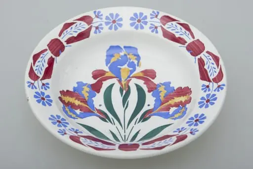 Farfurie de formă tronconică, ușor adâncită. Există două registre ornamentale, unul plasat de jur împrejurul buzei cu motive florale. Al doilea registru plasat în centru tot cu motive florale. Smălțuită. Cromatică: fond: alb; motive: albastru; verde; roșu; galben.