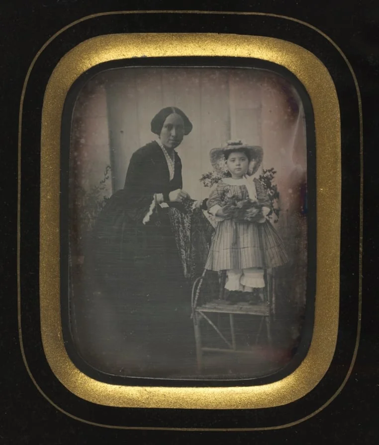 Child Standing on a Chair Holding Flowers, with Mother