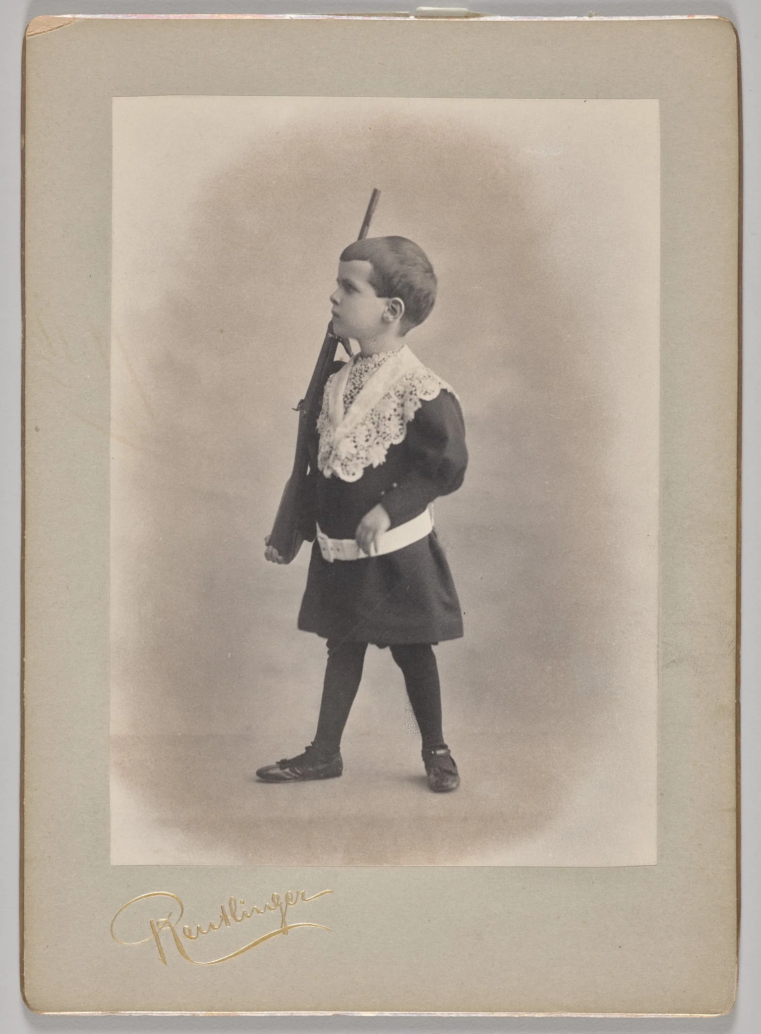 Untitled (young boy with lace collar and toy rifle), by Reutlinger Studios, 1890