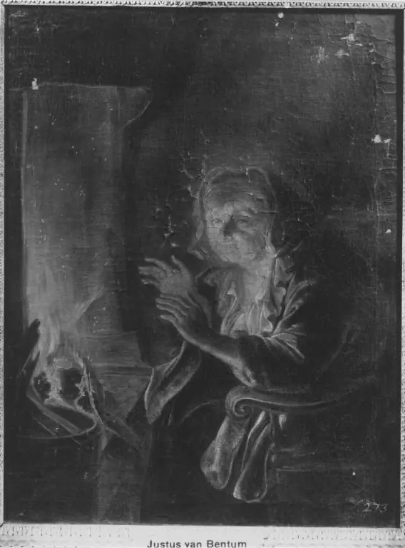 Old woman warming her hands at a fireplace