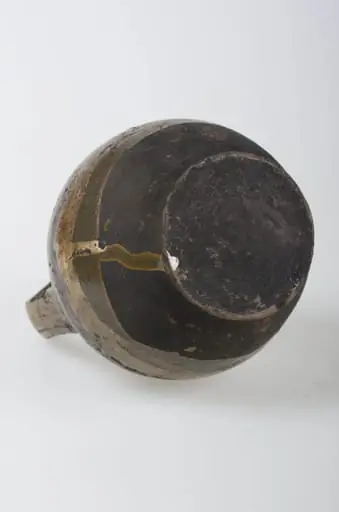 Recipient ceramic de formă sferică cu o toartă ce pornește de la baza buzei, printr-un inel, și se prinde de corp deasupra diametrului maxim. Buza este înaltă și relativ îngustă. Decorul este compus din motive geometrice (liniare, curbilinii) pictate, plasate pe toată suprafața obiectului. Pe alocuri sunt prezente pete de smalț. Vasul este smălțuit la exterior. Cromatică: fond: maron; bej; motive: maron închis, verde, galben.