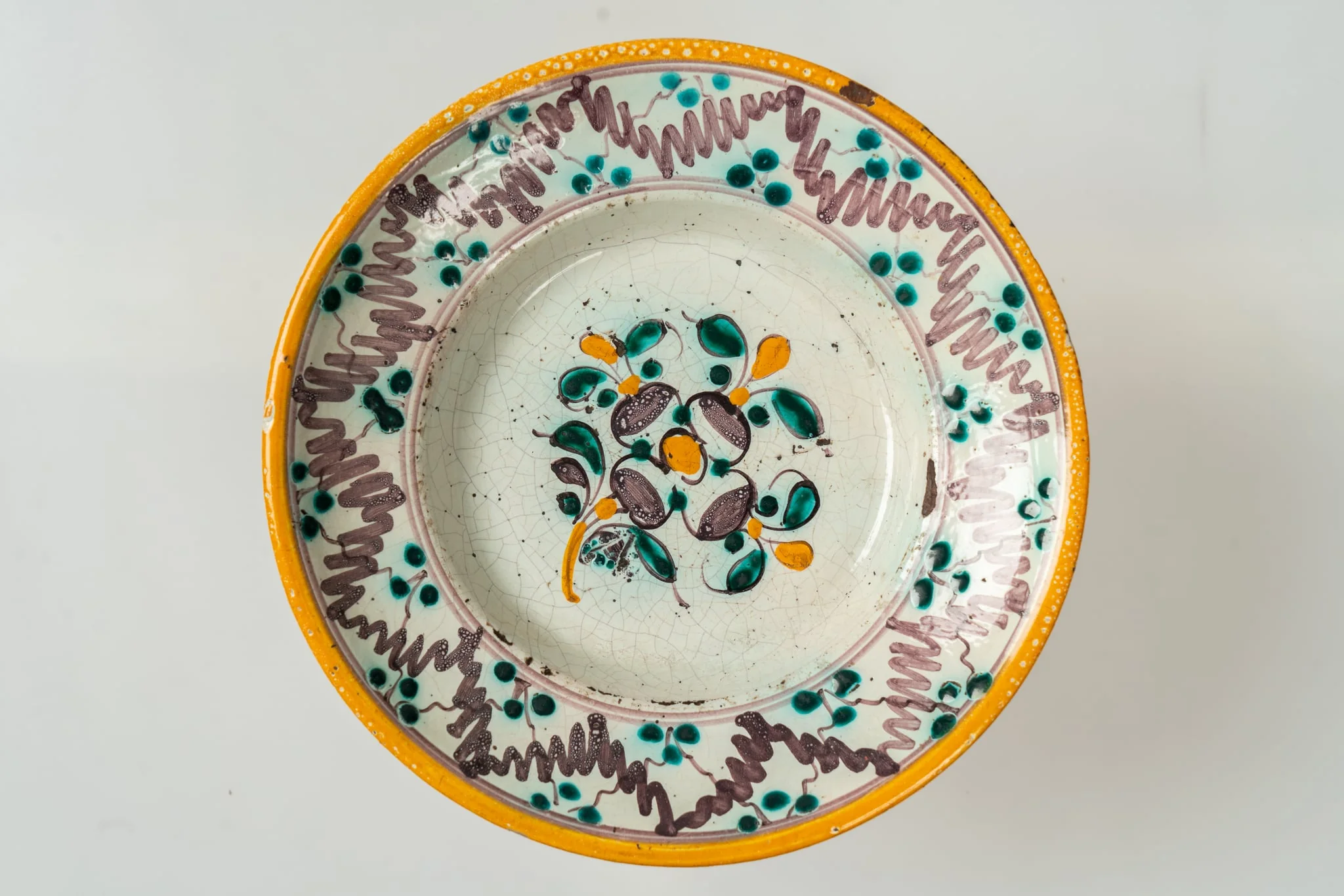 Farfurie de formă semi-adâncă, cu buza lată, răsfrântă. Decorul, dispus pe un fond alb, prin pictare, este format din motive florale fin stilizate (flori și frunze), dispuse central, pe fundul farfuriei, și motive geometrice pe buza acesteia (linii vălurite, puncte, cercuri concentrice). Cromatica decorului: alb, verde-turcoaz, brun, galben-ocru., by Unknown, 1850