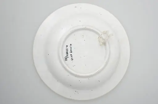 Farfurie din porțelan, de formă tronconică, întrebuințată în gospodărie la decorarea pereților casei. În interior se identifică un decor fitomorf, motive florale și vegetale, precum și un decor geometric. Motive florare sunt dispuse în trei registre pe margine, încadrate de un cerc negru; în centru este decorat cu trei flori albastre cu frunze verzi. Cromatică: fond: alb; motive: albastru, negru, verde.
