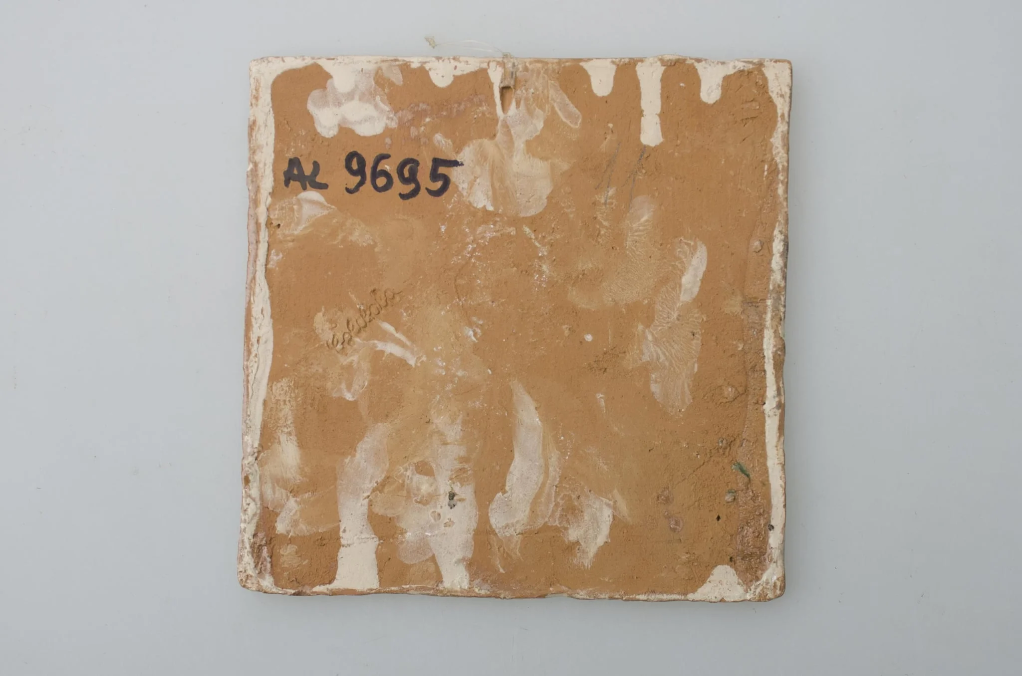 Piesă ceramică de formă pătrată, smălțuită și angobată, laturile pătratului fiind marcate de două chenare, primul vălurit, al doilea în linie dreaptă. Ornamentată cu motive zoomorfe și floral-vegetale, după fabula lui La Fontaine, Vulpea și barza: o vulpe care bea dintr-un ulcior și o barză care mânâncă dintr-un vas plat aflat pe o măsuță joasă. Pe două din colțuri, două flori completează pictura. Motivele au fost la început incizate, iar apoi pictate. Pe spate, cahla este prevăzută cu un orificiu pentru prinderea aței. Tot aici, este inscripționat numele meșterului olar, "Colibaba". Cromatică: fundal alb; motive: verde, galben, maro, cărămiziu.